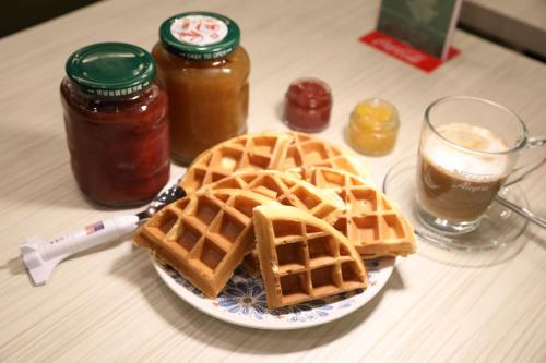a table with a plate of waffles and a glass of syrup at Jack Castle in Tainan