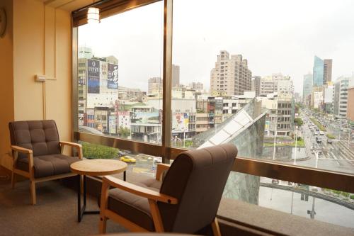 um quarto com duas cadeiras e uma mesa e uma grande janela em Trip GG Hostel em Kaohsiung