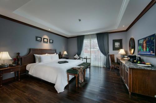 a bedroom with a large white bed and a desk at La Sinfonía Majesty Hotel and Spa in Hanoi