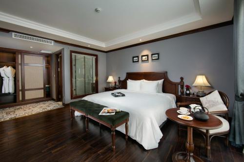 a bedroom with a large white bed and a table at La Sinfonía Majesty Hotel and Spa in Hanoi