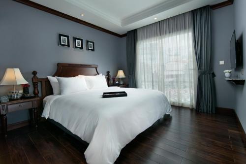 a bedroom with a large white bed and a window at La Sinfonía Majesty Hotel and Spa in Hanoi