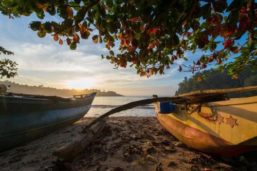 two boats sitting on a beach near the water at Gold ocean house in Hiriketiya