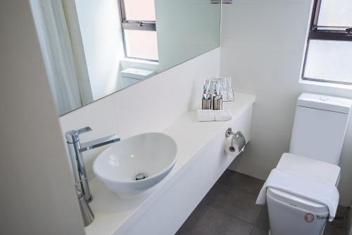 a white bathroom with a sink and a mirror at Travelodge Kowloon in Hong Kong