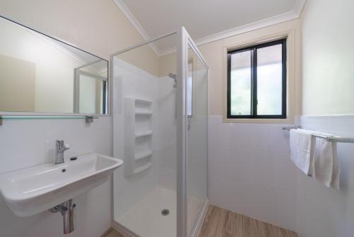 a white bathroom with a sink and a shower at Capricorn Caves in Rockhampton