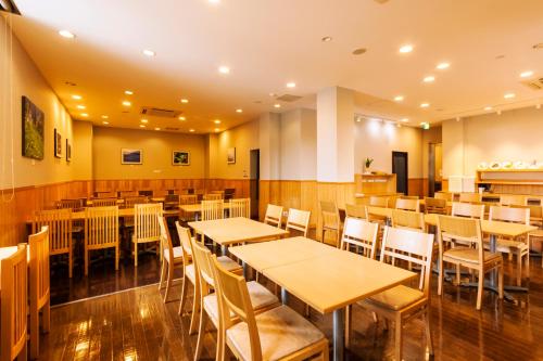 una sala da pranzo con tavoli e sedie in legno di Komagane Premont Hotel a Komagane