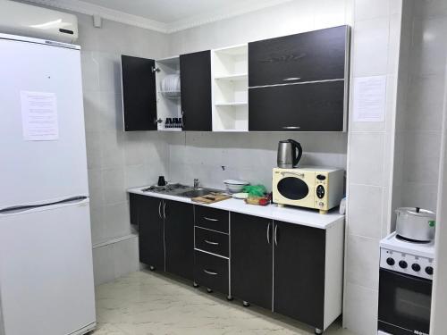 a small kitchen with a microwave and a refrigerator at Elite Hostel in Astana