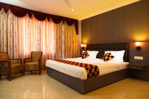 a hotel room with a bed and two chairs at Hotel Gopalapuram International in Pollāchi