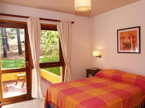a bedroom with a bed and a sliding glass door at Cabañas Entreverdes in Villa Gesell