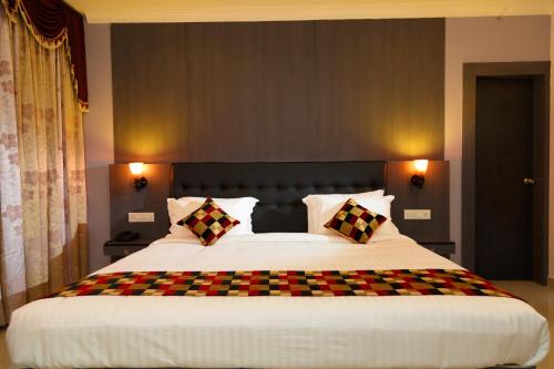 a bedroom with a large bed with checkered pillows at Hotel Gopalapuram International in Pollāchi