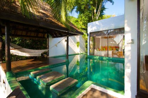 a swimming pool next to a house with a hammock at Koh Tao Cabana in Koh Tao