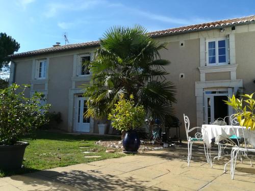 a house with a table and chairs and a palm tree at la Rosaliere in Chabournay