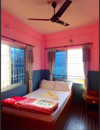 a bedroom with a bed with pink walls and windows at Sweet Dreams Guest house in Pokhara
