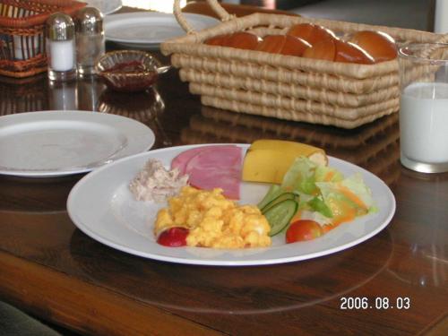ein Teller mit Lebensmitteln auf einem Holztisch mit Milch in der Unterkunft Pension Rapan in Katashina