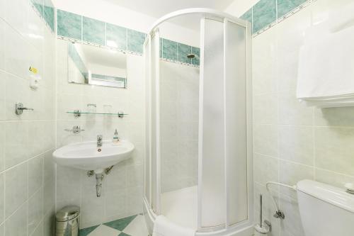 a white bathroom with a shower and a sink at Hotel Tábor in Tábor