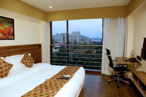 a hotel room with a bed and a desk and a window at Hotel Mumbai House Andheri East, Mumbai in Mumbai