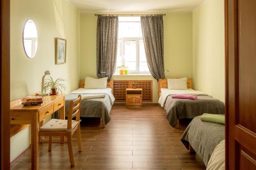 Zimmer mit 2 Betten, einem Schreibtisch und einem Fenster in der Unterkunft Zaya Hostel in Ulaanbaatar