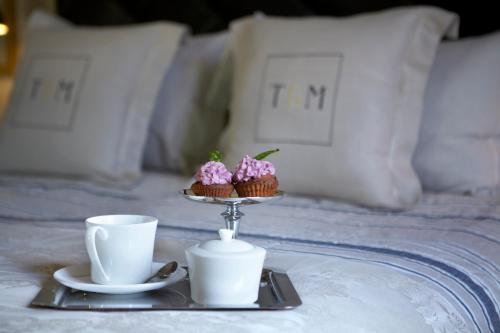 a tray with cupcakes and two cups on a bed at Torri E Merli Boutique Hotel in Lákka