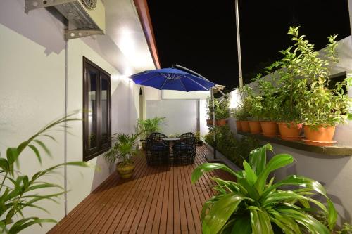 an outdoor deck with a blue umbrella and potted plants at Island Home Inn in Ukulhas