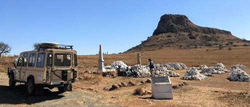 a military vehicle parked in a field with sheep at Fugitives Drift Guest House in Rorkeʼs Drift