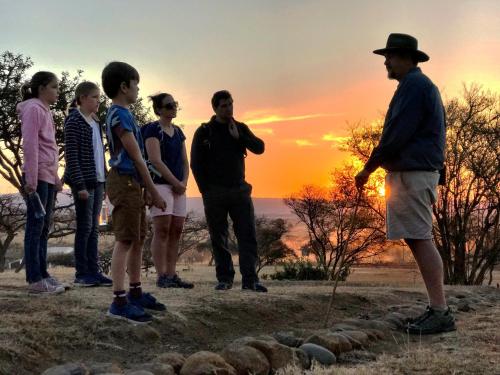 a group of people standing on a hill at sunset at Fugitives Drift Guest House in Rorkeʼs Drift