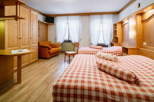 ein Hotelzimmer mit zwei Betten und einer Couch in der Unterkunft Hotel Posta in Sappada