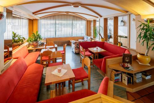 a restaurant with red couches and tables at Hotel Posta in Sappada