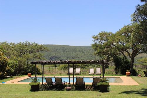 eine Gruppe von Stühlen unter einem Pavillon neben einem Pool in der Unterkunft Fugitives Drift Guest House in Rorkeʼs Drift