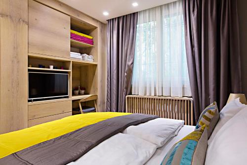 a bedroom with a bed and a tv and a window at City Center Apartment Sarajevo Accross BBI Shopping Mall in Sarajevo
