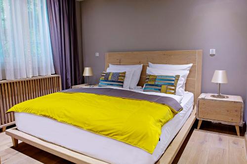 a bedroom with a large bed with a yellow blanket at City Center Apartment Sarajevo Accross BBI Shopping Mall in Sarajevo