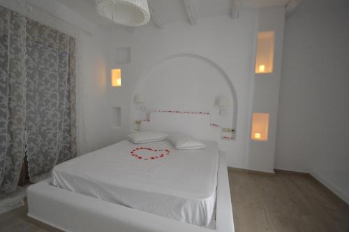 a white bedroom with a bed with a red heart on it at Bianca Suite & Home in Psinthos