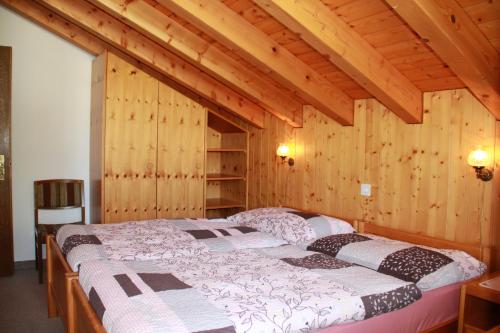 ein Schlafzimmer mit einem Bett in einem Zimmer mit Holzwänden in der Unterkunft Haus Pan in Zermatt