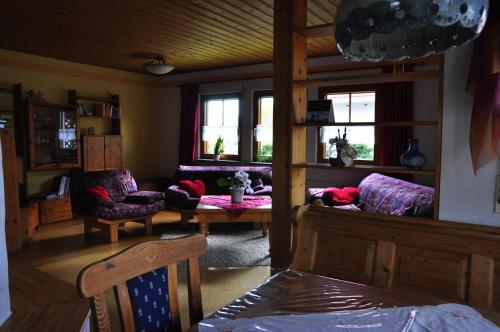 - un salon avec un canapé, des chaises et des fenêtres dans l'établissement Ferienwohnung am Bimbach, à Herzogenaurach