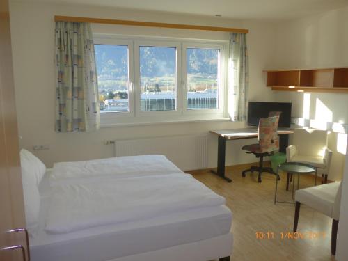 Habitación de hotel con cama, escritorio y ventana en Kolpinghaus Spittal en Spittal an der Drau