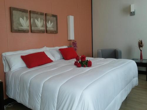 a large white bed with red pillows and flowers on it at Hotel Puerta de Ocaña in Ocaña