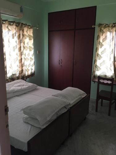 a bedroom with a bed and a cabinet and a chair at Nalanda Tulip in Kolkata