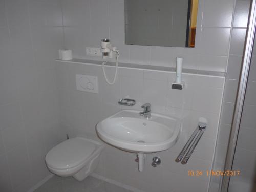 a white bathroom with a toilet and a sink at Kolpinghaus Spittal in Spittal an der Drau