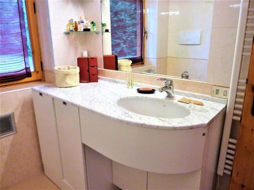 La salle de bains est pourvue d'un lavabo blanc et d'un miroir. dans l'établissement Andromeda, à Stresa