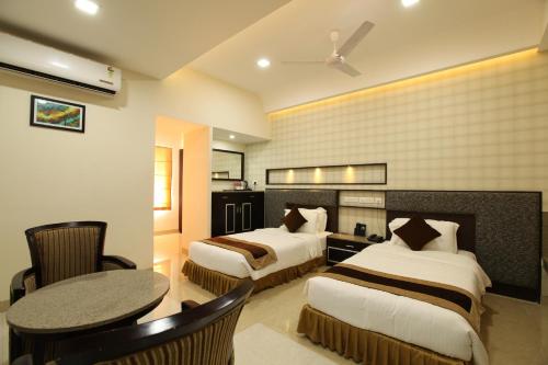 a hotel room with two beds and a table at Hotel Southern Residency in Kelambākkam