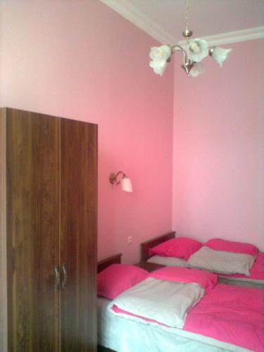 1 dormitorio con 2 camas y pared de color rosa en Vita, en Tiflis