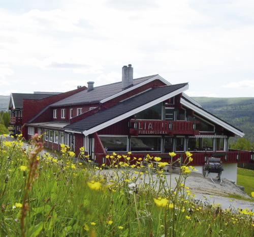 Une grande grange rouge avec des fleurs devant elle dans l'établissement Lia Fjellhotell, à Geilo