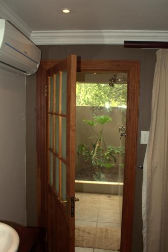 a bathroom with a door with a plant in a window at Tuskers Bush Lodge B&B in Hartbeespoort