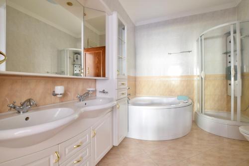 La salle de bains est pourvue de 2 lavabos, d'une baignoire et d'une douche. dans l'établissement Luxury Apartment by Hi5 - Lovag Suites, à Budapest