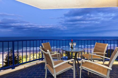 a balcony with chairs and a table and the ocean at Surf Regency in Gold Coast