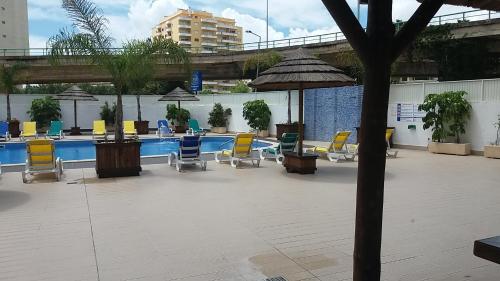 a pool with chairs and tables and an umbrella at Gaivota Sun in Portimão