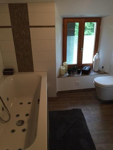 ein Bad mit einer Badewanne und einem WC in der Unterkunft LaMaisonRouge chambre d'hôtes in Cormondreche
