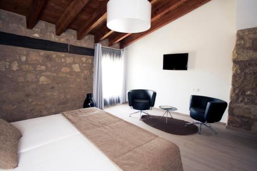 a bedroom with a bed and two black chairs at Hotel Restaurante Masía la Torre in Mora de Rubielos