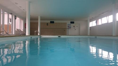 a large swimming pool with blue water in a building at Domaine de l Emeraude in Le Tronchet