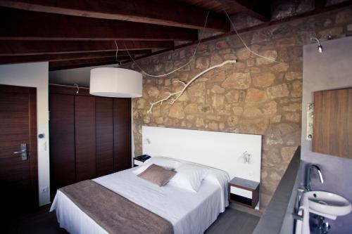 a bedroom with a large bed and a stone wall at Hotel Restaurante Masía la Torre in Mora de Rubielos