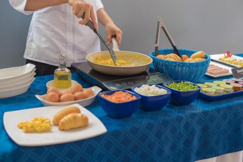 a person preparing food on a table with bowls of food at Hotel Buena Vista Express in Bucaramanga