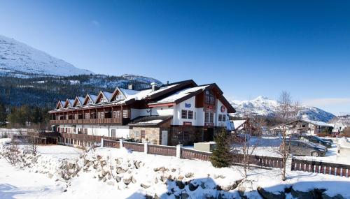 a large building in the snow with a fence at Fanitullen Hotel in Hemsedal